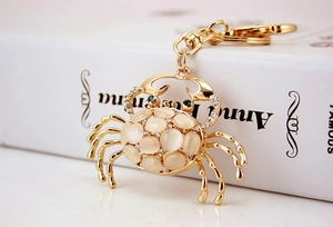 Detailed view of crab keychain with golden metal, cat eye stones and sparkling rhinestones