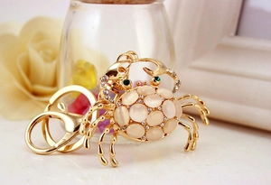 Close-up of golden crab keychain with opal shell and crystal accents on a metal ring