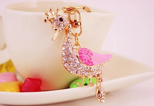 Detailed view of golden swan keychain with pink enamel wings and sparkling rhinestones