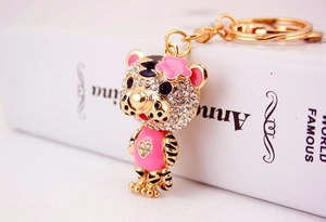 Détail d'un porte-clés tigre doré avec émail rose et strass brillants sur fond de livre