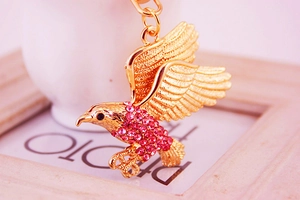 Nahaufnahme Adler Schlüsselanhänger aus Gold mit rosa Strasssteinen und Flügeln