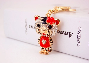 Détail macro du porte-clés tigre doré avec strass et fleur en émail rouge brillant