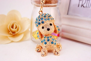 Detail of golden metal poodle keychain with blue crystals and refined lobster clasp