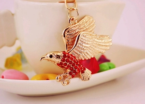 Detailansicht goldener Adler-Schlüsselanhänger mit roten Kristallen und Federstruktur