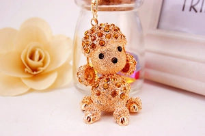 Close-up of golden metal poodle keychain with orange rhinestones and rotating hook