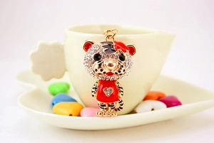 Détail d'un porte-clés tigre mignon avec strass et émail rouge accroché à une tasse