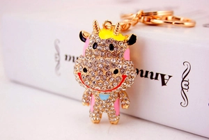 Détail d'un porte-clés vache en métal avec strass blancs étincelants et finitions en émail