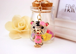 Détail d'un porte-clés tigre mignon serti de strass blancs et portant un pull rose