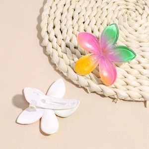 Pinze per capelli a fiore di plumeria sfumata su tappetino in paglia intrecciata