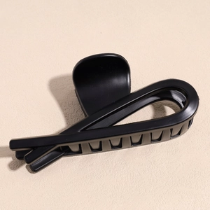 Detail of minimalist matte black shark hair claw clip with crisscross spiral design