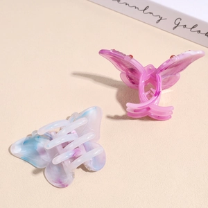 Elegant butterfly hair claws with purple gradient and rhinestones on beige surface