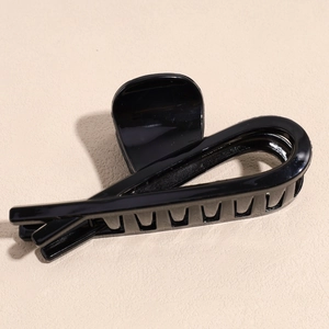 Close-up of elegant glossy black hair claw clip with a twisted streamlined design