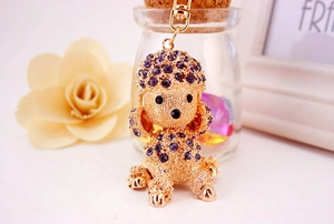 Close-up of golden metal poodle keychain with sparkling purple rhinestones