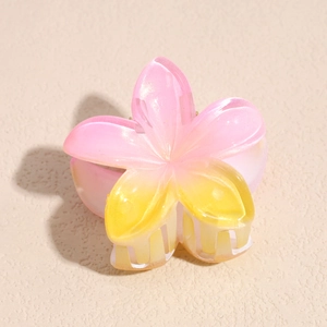 Macro detail of pearlescent gradient frangipani hair claw with pink and yellow tones