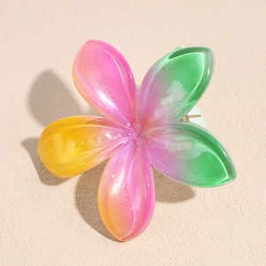 Dettaglio della molletta a fiore plumeria sfumata rosa e verde in resina perlata