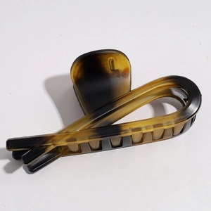 Macro detail of tortoiseshell hair claw clip with amber gradient finish and geometric design