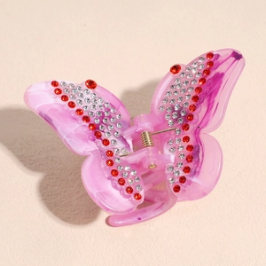 Detailed macro of a butterfly hair claw with pink marble texture and sparkling rhinestones