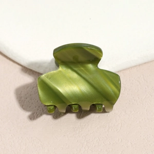 Detail view of grass green acetate hair claw clip with silk texture and cat-eye luster