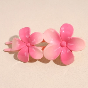 Détail du clip à cheveux avec fleurs dégradées roses et finition en résine polie