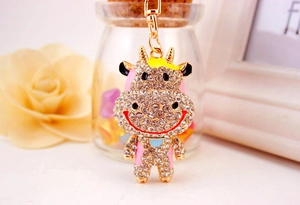 Macro d'un porte-clés vache mignon en métal avec strass brillants et émail rose