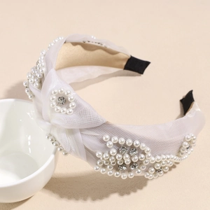 Detail of white mesh headband featuring decorative pearls, crystals and a twist knot design