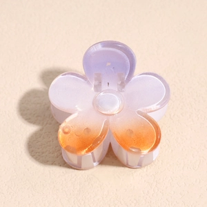 Close-up of a gradient acrylic frangipani hair claw clip with purple and orange tones