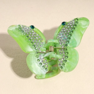 Detailed macro of a green butterfly hair claw clip with rhinestones and metal spring