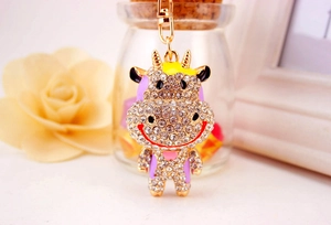 Détail d'un porte-clés vache doré serti de strass blancs et détails en émail violet