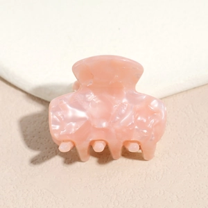 Macro detail of pink marble acetate hair claw showing smooth texture and grip teeth