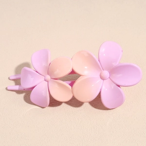 Détail de deux épingles à cheveux fleurs rose mat avec structure de peigne à quatre dents