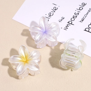 Iridescent plumeria flower hair claws with pearl finish for elegant beach styling