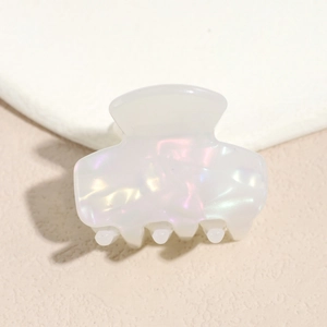 Detail view of cream white acetate hair claw with iridescent texture and glossy finish