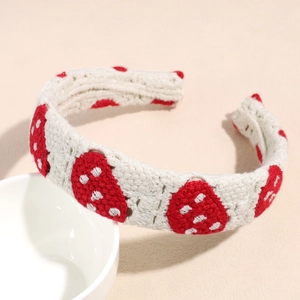 Detail of handmade crochet headband featuring red strawberry patterns on white knit fabric