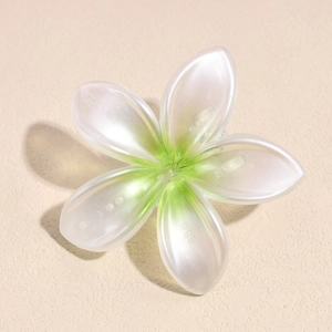 Detalle de la pinza de pelo plumeria blanco perla con degradado verde y acabado nacarado