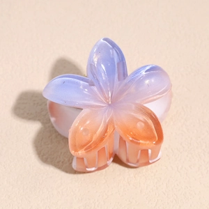 Macro shot of gradient purple and orange plumeria hair claw clip with pearlescent finish