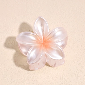 Detail of pearlescent pink flower hair claw with gradient orange center for beach style