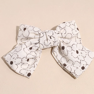 Detail der beigefarbenen Stoff-Haarspange mit braunem Blumenmuster und Schleifendesign