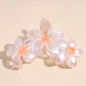 Détail d'une élégante pince à cheveux en forme de fleur de frangipanier rose nacré