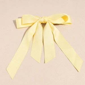 Dettaglio del fermaglio per capelli a fiocco in raso giallo chiaro con nastri lunghi