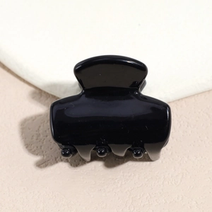 Macro shot of a high-gloss black acetate hair claw clip with a sleek polished finish