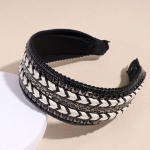 Detail of woven headband featuring black and white cords with metal pyramid studs and rhinestones