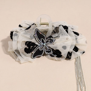Détail de la pince à cheveux en tulle blanc à pois avec de longs pompons en strass brillants