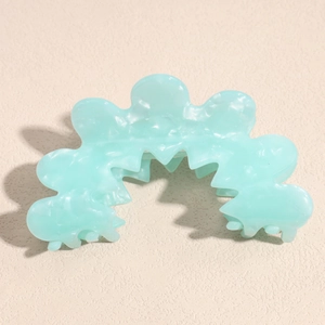 Macro detail of wave-shaped mint green acetate hair claw with marble texture finish