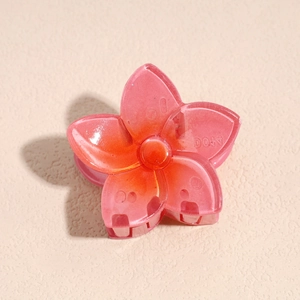 Macro d'une pince à cheveux en fleur de frangipanier avec un dégradé rose et orange