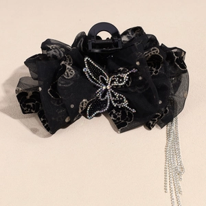 Détail de la pince à cheveux noire avec papillon en strass et longs accents de glands