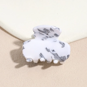 Detail of white and grey marble texture on acetate hair claw clip with glossy finish