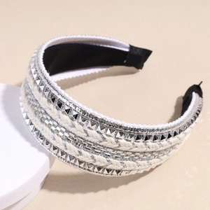Detail view of woven beige headband featuring silver geometric studs and sequin trim finish