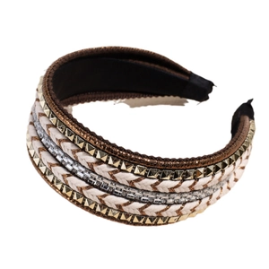 Bohemian wide braided headband with gold rivets and crystals on a plain background