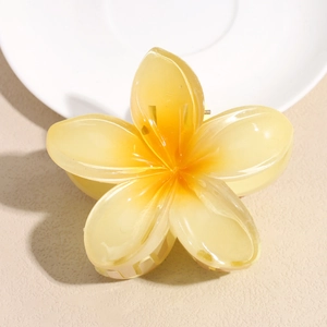 Close-up of translucent frangipani flower hair claw clip with yellow gradient finish