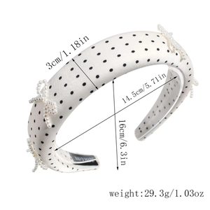 Close-up of white polka dot headband with pearl bows and handmade label detail